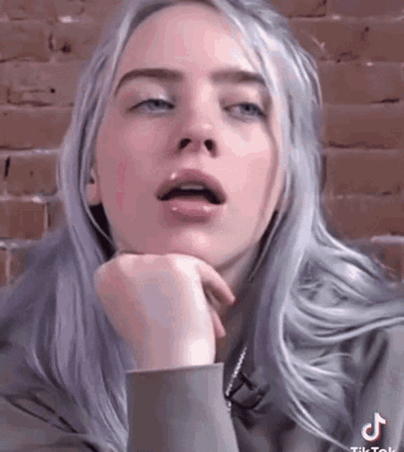 a close up of a woman 's face with a hand on her chin .