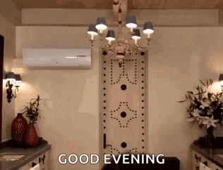 a room with a chandelier and the words good evening written on the wall .