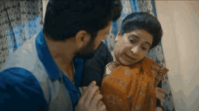 a man and a woman are sitting next to each other in a room and the man is touching the woman 's chest .
