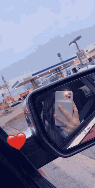 a woman is taking a selfie in the rear view mirror of her car at a gas station
