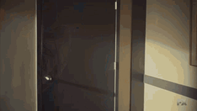 a person is standing in a room with a fx logo on the wall behind them