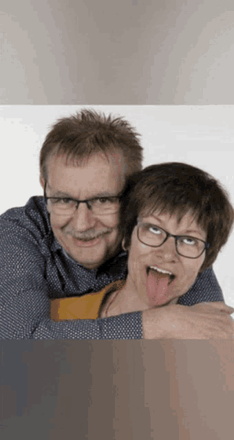 a man and a woman are posing for a picture with the woman sticking her tongue out