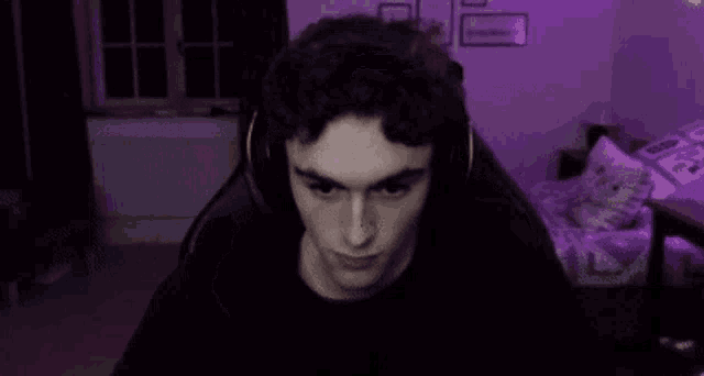 a young man wearing headphones is sitting in a gaming chair covering his mouth .