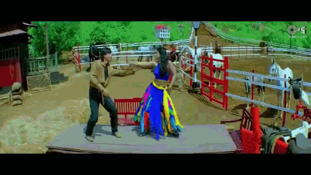 a man and a woman are dancing in a ranch with horses .