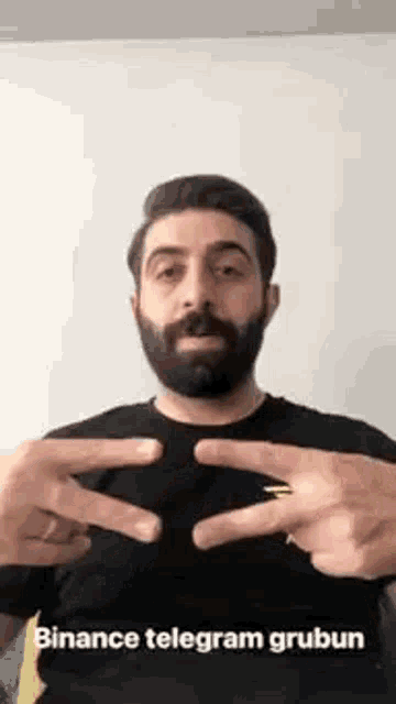 a man with a beard and a ring on his finger is making a peace sign .