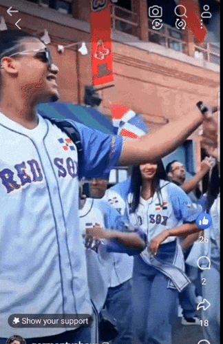 a man wearing a red sox jersey stands in front of a crowd