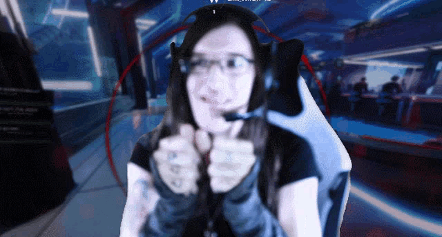 a woman wearing headphones and a microphone is giving a thumbs up