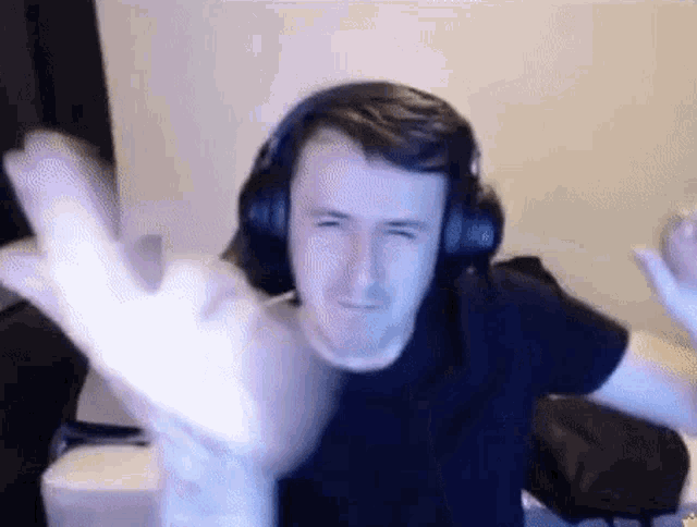 a man wearing headphones is making a funny face and giving the middle finger .