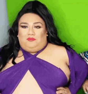 a woman in a purple dress is looking at the camera .