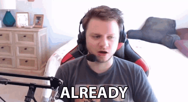 a man wearing headphones and a shirt that says already is sitting in front of a microphone