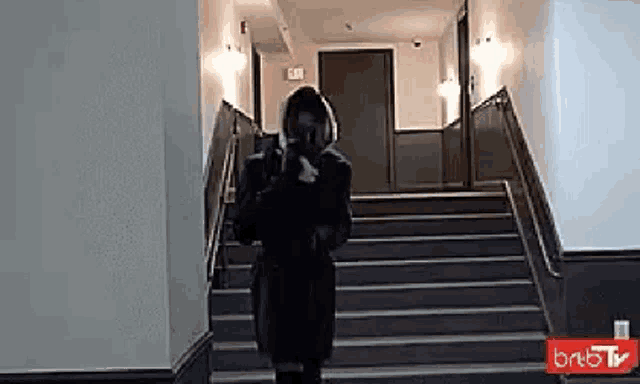 a woman is walking down a set of stairs in a hallway .