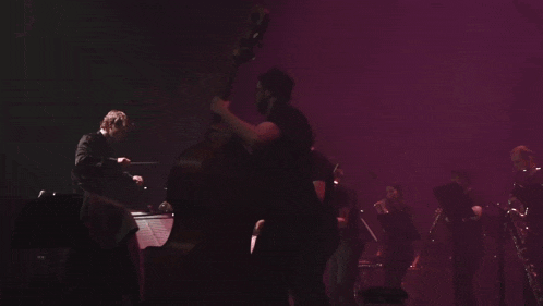 a man playing a double bass in front of a band
