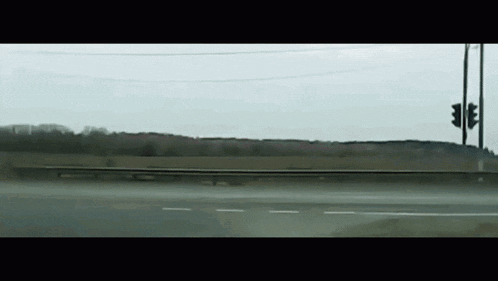 a car is driving down a highway with a red light in the distance