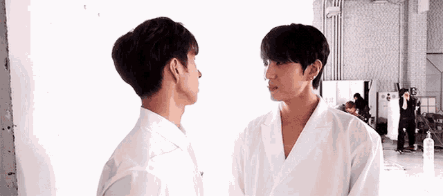 two men in white shirts are standing next to each other in a room .