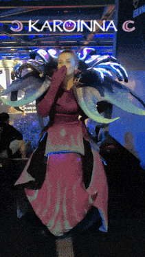 a woman in a costume stands in front of a sign that says karoinna