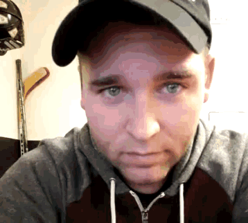 a man wearing a baseball cap and a hoodie is looking at the camera