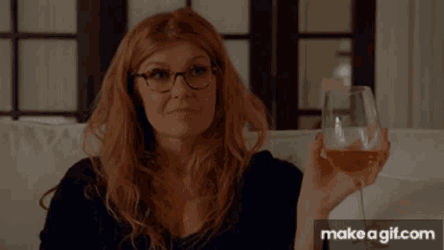 a woman sitting on a couch holding a glass of wine ..