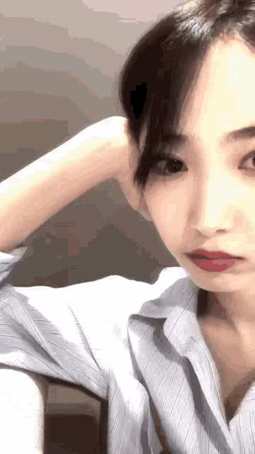 a close up of a woman 's face with her hand on her head and red lips .