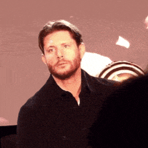 a man with a beard is wearing a black shirt and a black jacket .