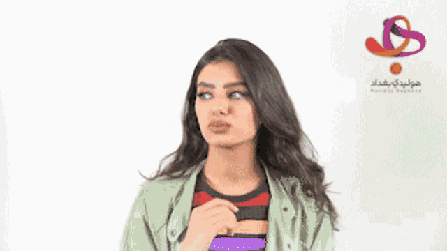 a woman is standing in front of a wall with arabic writing