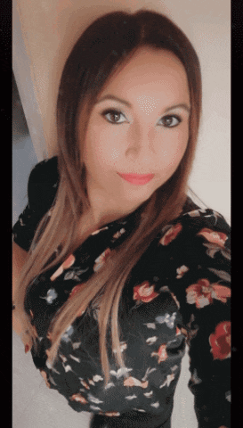 a woman wearing a black floral shirt is taking a selfie