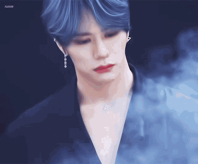 a man with blue hair and red lips is surrounded by smoke