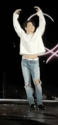 a man in a white shirt and ripped jeans is dancing on a stage