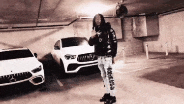 a man is standing in a parking garage in front of a row of cars .
