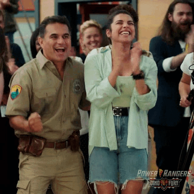 a man and a woman are standing next to each other and laughing in a crowd .