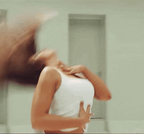 a woman in a white tank top is standing in a room