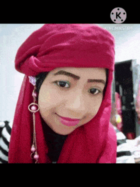 a woman wearing a red head scarf and earrings is smiling for the camera