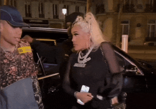 a woman wearing a black shirt that says nicki minaj talks to a man