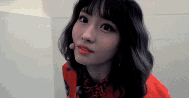 a close up of a woman 's face with a red jacket and leopard print scarf .