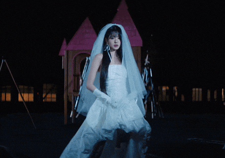 a woman in a bride 's dress stands in front of a fire