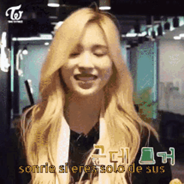 a woman with blonde hair is smiling with a twice logo in the background