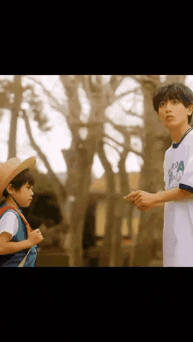 two young boys are standing next to each other in a park .