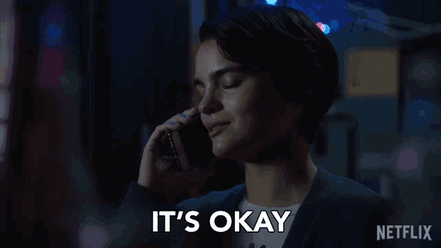 a woman talking on a cell phone with the words " it 's okay " written below her