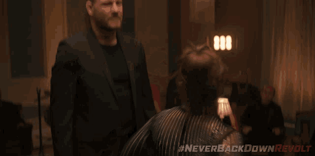 a man in a suit is standing next to a woman in a boxing ring with the hashtag neverbackdownrevolt