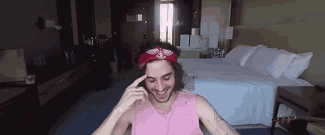 a man wearing a pink shirt and a red bandana is smiling