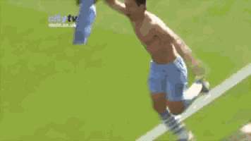 a shirtless soccer player is running on the field with a flag in his hand