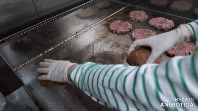 a person is cooking hamburger patties on a grill and the words made in animotica are visible