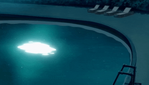 a swimming pool is lit up at night with a light in the middle