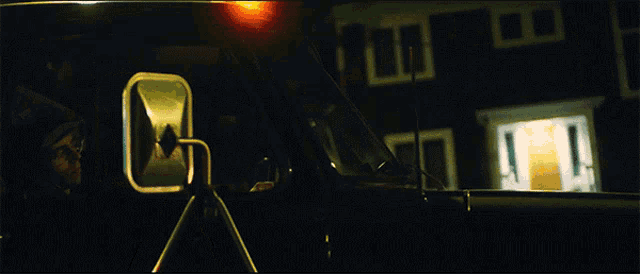 a car is parked in front of a house with a yellow light on the side of it