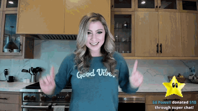 a woman in a kitchen wearing a good vibe sweatshirt