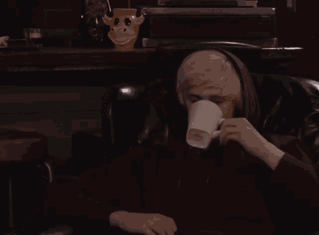 a person drinking from a white mug with a giraffe on top of it