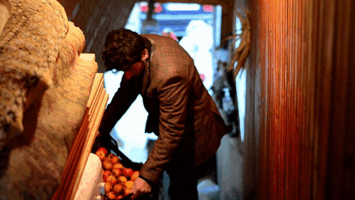 a man in a suit is reaching into a box of fruit