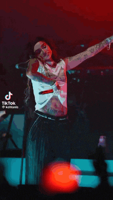a woman is standing on a stage with her arms outstretched while singing into a microphone .