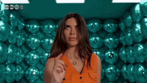 a woman in an orange dress is standing in front of a wall of disco balls with a cbs logo in the background