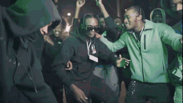 a group of young men are dancing in a dark room while wearing hoodies and masks .