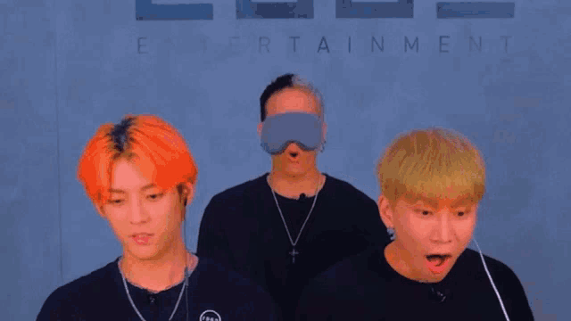 three men are standing in front of a sign that says wow on it